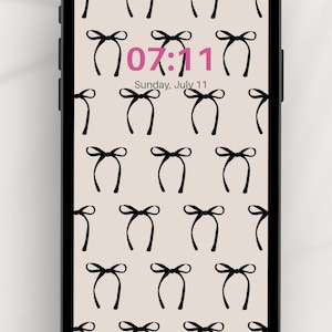 May include: A smartphone displaying a digital clock showing the time 07:11 and the date Sunday, July 11. The background is a beige pattern of black bows.