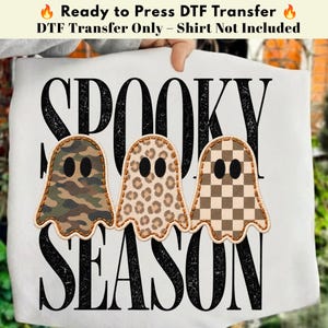 Può includere: Un trasferimento DTF pronto per l'applicazione con il testo SPOOKY SEASON in lettere nere dall'effetto usurato. Al centro si trovano tre sagome di fantasmi, ognuna con un motivo diverso: mimetico, leopardato e a scacchi marroni e beige.