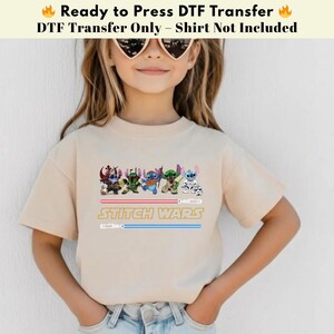 Puede incluir: Una camiseta de color beige claro con un dise&ntilde;o de "Stitch Wars". El dise&ntilde;o incluye personajes de dibujos animados y el texto "STITCH WARS" en amarillo. La parte superior tambi&eacute;n tiene el texto "Ready to Press DTF Transfer" en negro.