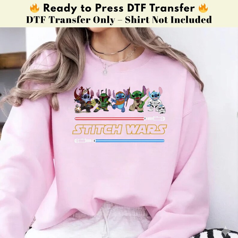Puede incluir: Una sudadera rosa claro con un dise&ntilde;o de "Stitch Wars". El dise&ntilde;o presenta personajes de dibujos animados disfrazados de personajes de Star Wars, con el texto "STITCH WARS" en dorado y l&iacute;neas azules estilo sable l&aacute;ser.