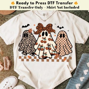 May include: A cream-coloured t-shirt with three ghost designs. The ghosts have patterns including leopard print, cherries, and a checkered design. The text "Ready to Press DTF Transfer" is at the top. Bats and flowers are also included.