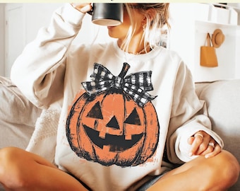 May include: A cream-coloured sweatshirt with a distressed orange jack-o'-lantern design and a black and white plaid bow. The text at the top reads "Ready to Press DTF Transfer" and "DTF Transfer Only - Shirt Not Included."