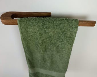 May include: A wooden towel rack with a curved design. A green towel is hanging on the rack.
