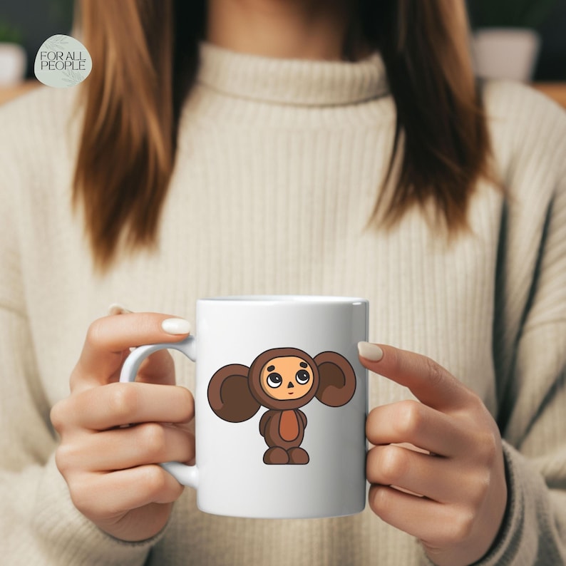 May include: White ceramic mug with a cartoon illustration of a brown furry character with large ears and a sad expression. The character is wearing a brown jumpsuit.
