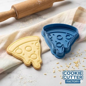 May include: A pizza slice-shaped biscuit and a blue plastic cookie cutter. The biscuit is light yellow with brown edges and round toppings. The cutter has a pizza slice shape with round cutouts. The text "COOKIE CUTTER FACTORY" is in the bottom right corner.