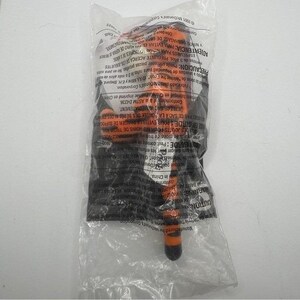 May include: An orange and black toy screwdriver is sealed in a clear plastic bag. The bag has printed text in multiple languages, including English and Spanish. The toy's handle is orange, and the tip is black. The bag is sealed.