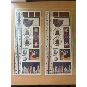 Puede incluir: Dos hojas de pegatinas con temática navideña. Cada hoja presenta elementos decorativos: cajas de regalo, campanas, copos de nieve, adornos, un reno y un paisaje urbano. Las pegatinas tienen una estética vintage, similar a un álbum de recortes.