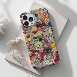 Könnte beinhalten: Dekorative Handyhülle mit einer Collage aus Charms, Herzen, Sternen und Sonnen in verschiedenen Farben. Die Hülle weist eine Mischung aus Texturen und Verzierungen auf und schafft ein einzigartiges und künstlerisches Design.
