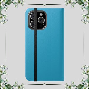 May include: A turquoise phone case with a black elastic strap. The case has a textured finish and a camera cutout. The phone case is designed to protect the phone from scratches and damage.