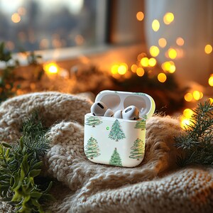 K&ouml;nnte beinhalten: Wei&szlig;e Airpod-H&uuml;lle mit einem Weihnachtsbaum-Muster. Die H&uuml;lle ist ge&ouml;ffnet und die Airpods befinden sich darin.
