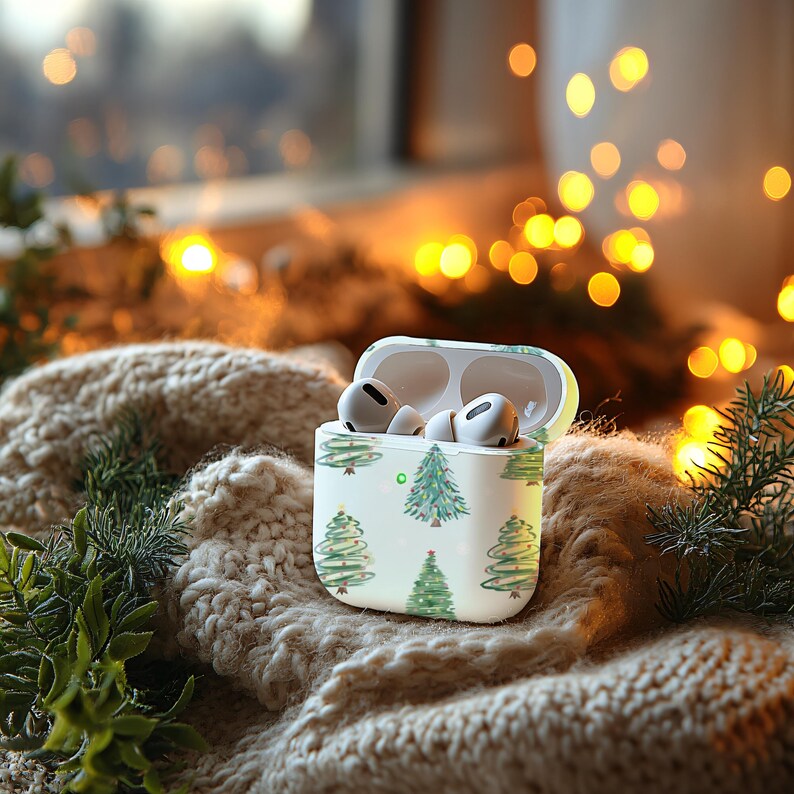K&ouml;nnte beinhalten: Wei&szlig;e Airpod-H&uuml;lle mit einem Weihnachtsbaum-Muster. Die H&uuml;lle ist ge&ouml;ffnet und die Airpods befinden sich darin.