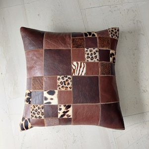 May include: A brown leather pillow with a patchwork design featuring various animal prints, including zebra, leopard, and cheetah.