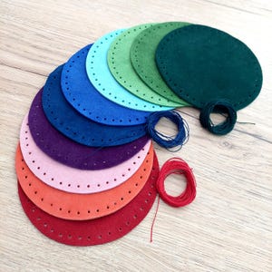 May include: A set of ten felt circles in various colors, including red, orange, pink, purple, blue, green, and teal. Each circle has a row of evenly spaced holes around the edge. The circles are arranged in a rainbow pattern, with the largest circle at the top and the smallest circle at the bottom. There are also spools of thread in various colors.