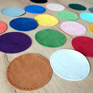 Peut inclure: Assortiment de dessous-de-verre ronds en feutre de différentes couleurs, notamment violet, bleu, vert, jaune, rouge, rose, marron et blanc. Les dessous-de-verre sont cousus sur les bords.