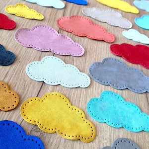 Può includere: Un set di 12 forme di nuvole in feltro di vari colori, tra cui rosso, blu, giallo, verde e grigio. Le nuvole sono tutte della stessa dimensione e forma, e sono perfette per l'artigianato o la decorazione.