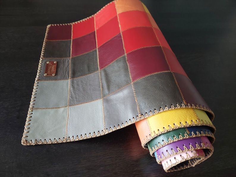 May include: A multi-colored leather patchwork rug with a stitched edge. The rug is rolled up, revealing the different colors of the patchwork.