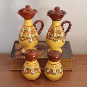 May include: Set of four ceramic kitchenware pieces in a yellow, brown, and orange color scheme. Two brown lidded jugs with a handle and two smaller salt and pepper shakers.