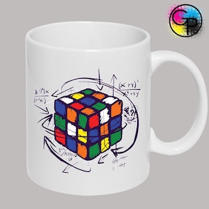 May include: White ceramic mug with a Rubik's Cube design, mathematical equations, and arrows. The mug has a curved handle and a glossy finish. The design includes the text "R U?K (F'N)" and "1st M355D UP".