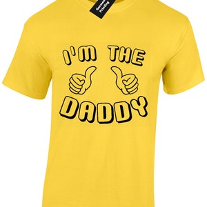 May include: Yellow t-shirt with black text that reads "I'm the Daddy" with two thumbs up symbols.