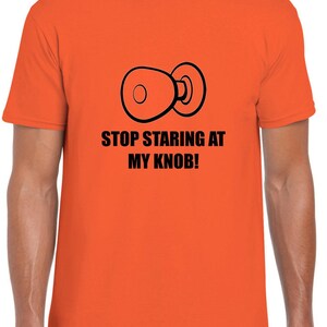 May include: Orange t-shirt with a black illustration of a door knob and the text "STOP STARING AT MY KNOB!"