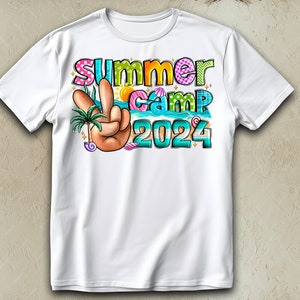 May include: White t-shirt featuring a colourful graphic design that reads "Summer Camp 2024". The design includes a peace sign, a palm tree, and seashells.