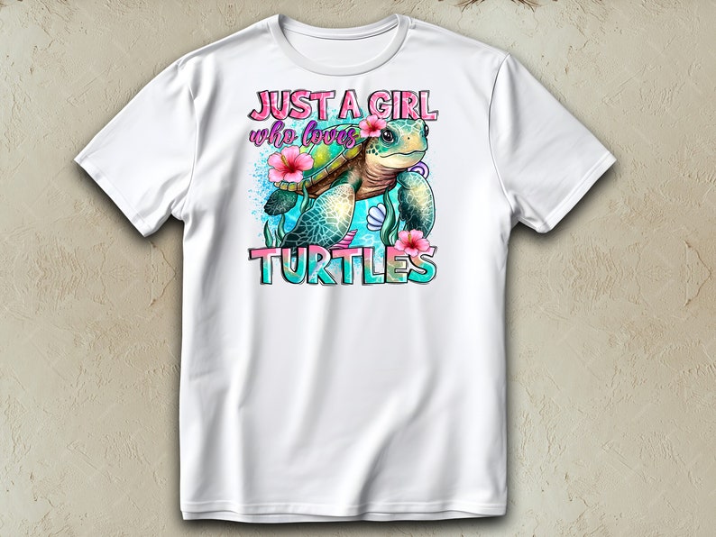 May include: White t-shirt featuring a colorful graphic of a sea turtle with pink flowers and the text "JUST A GIRL who loves TURTLES". The design includes blue and turquoise accents.