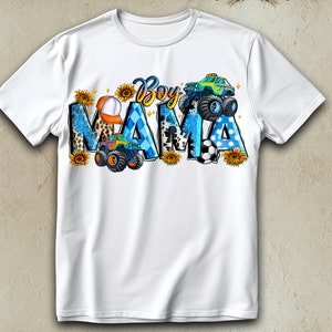 May include: White t-shirt with the words "Boy Mama" in a colorful design. The design includes monster trucks, sunflowers, a baseball cap, and a soccer ball. The letters are decorated with blue, black, and yellow patterns.
