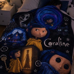 May include: A black fleece blanket featuring Coraline movie graphics, including the character in a yellow raincoat, a black cat, a house, a key, and buttons. The text Coraline is printed in white with a button replacing the letter o.