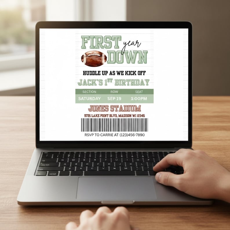 May include: A laptop displays a football-themed birthday invitation. The invitation reads "First Year Down" with a football graphic. Details include "Jack's 1st Birthday," date, time, and stadium information. A hand is using the laptop.