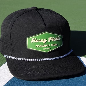 May include: Black and green baseball cap with a white rope detail and a green patch that says "Horny Pickle Pickleball Club Est. 1963"
