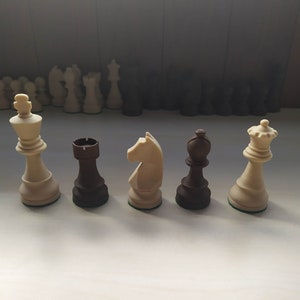 May include: A set of chess pieces, including a white king, queen, knight, and a black rook and bishop. The pieces are made of wood and have a traditional design.
