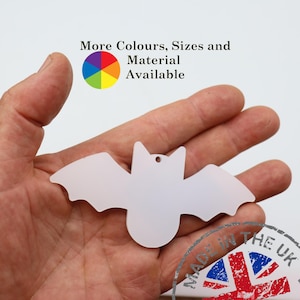 May include: A white bat-shaped decoration with a small hole for hanging. The image includes the text "More Colours, Sizes and Material Available" and a colour wheel. A stamp that says "Made in the UK" is also visible.