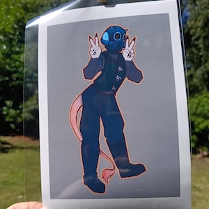 May include: A print of a cartoon character in a dark blue outfit with a gas mask, making a peace sign with both hands. The character has a pink tail and is standing on a gray background.