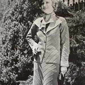 May include: A vintage black and white photograph of a woman wearing a tailored suit with a matching skirt and jacket. The suit features a chevron pattern. She is also wearing a hat and holding a small clutch.