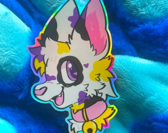 May include: A holographic sticker of a cartoon animal with white fur, black spots, yellow and purple markings, and a pink ear. The animal is wearing a pink collar with a gold bell.