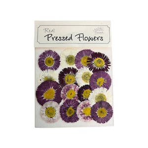 May include: A package of real pressed flowers, featuring a variety of colorful blooms. The flowers are in shades of purple, white, and yellow, with a visible texture. The package has a white label with the text "Real Pressed Flowers".