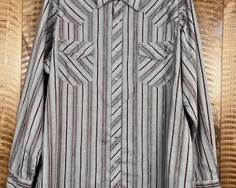 May include: A long-sleeved button-down shirt with a striped pattern in gray, burgundy, and white. The shirt has two chest pockets and a classic collar. The shirt is hanging on a white hanger.