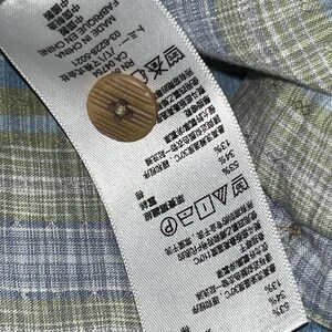 May include: Close-up of a fabric tag with a brown button. The tag includes text in multiple languages, care instructions, and fabric composition percentages: 53% Lyocell, 34% Silk, and 13% Cotton. The tag reads "Made in China".