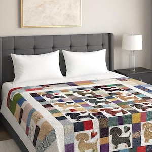 Pu&ograve; includere: Una colorata trapunta patchwork con un motivo ripetuto di cani bassotti. La trapunta &egrave; realizzata con vari quadrati di tessuto nei toni del rosso, blu, verde e marrone. La trapunta &egrave; su un letto con cuscini bianchi e una testiera grigia.