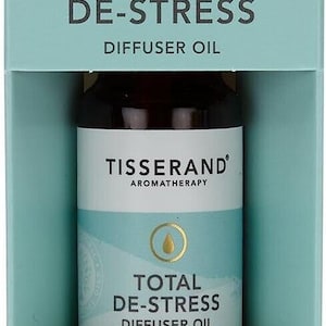 May include: A small brown glass bottle of Tisserand Total De-Stress Diffuser Oil. The bottle is labelled with the brand name and product name. The bottle contains a blend of geranium, orange, and nutmeg essential oils. The bottle is 9 ml or 0.30 fl. oz.