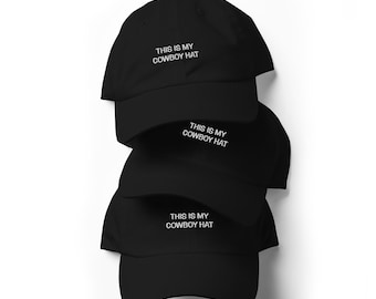 May include: Three black baseball caps stacked on top of each other. Each cap has white embroidered text that reads "THIS IS MY COWBOY HAT".