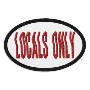 May include: Embroidered patch with the words "LOCALS ONLY" in red, stylized text. The text is centered on a white oval, framed by a black border. The patch is likely designed to be sewn or ironed onto clothing or accessories.