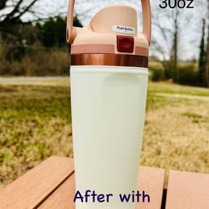 Puede incluir: Una botella de agua aislada de 887 ml con tapa de botón. La botella es de color crema con una banda color cobre y un asa marrón. El texto "After with sleeve" está impreso en la botella.