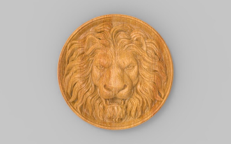 Op de afbeelding: Een ronde houten plaquette met een gegraveerd leeuwenhoofd in het midden. De leeuwenmanen zijn gedetailleerd en het gezicht is woest.