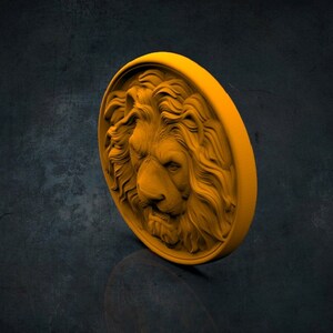Op de afbeelding: Een ronde, gouden, decoratieve wandplaat met een gedetailleerd, driedimensionaal beeldhouwwerk van een leeuwenkop.