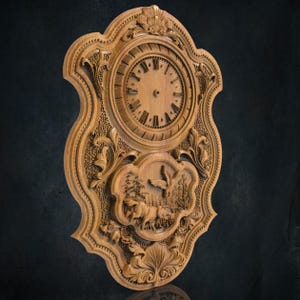 Può includere: Un orologio da parete in legno con intagli intricati. Il quadrante dell'orologio è circondato da una cornice decorativa con motivi floreali. Il quadrante dell'orologio ha numeri romani e un uccello in volo è intagliato sotto il quadrante dell'orologio.