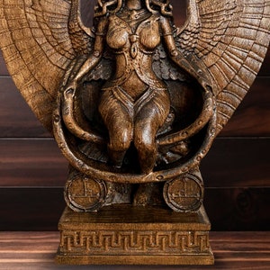 May include: A wooden sculpture of a winged female figure with a snake wrapped around her body. The sculpture is painted in a dark brown color and has a detailed design.