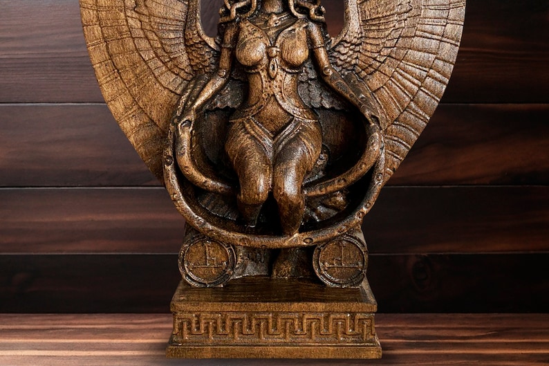 May include: A wooden sculpture of a winged female figure with a snake wrapped around her body. The sculpture is painted in a dark brown color and has a detailed design.