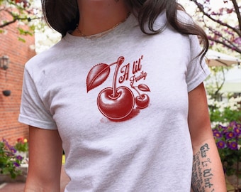 May include: A white cropped t-shirt with a red cherry graphic and the text "A lil' Fruity".