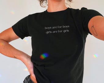 May include: Black crew neck t-shirt with the text "boys are for boys girls are for girls" in a white, minimalist font. The shirt is made of a soft material and is being worn.